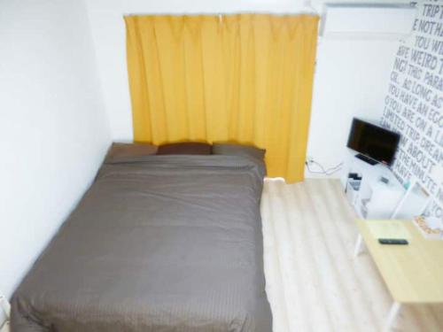 1 dormitorio con cama y cortina amarilla en The Mickey Carlton Ohashi Alpha Coat - Vacation STAY 15163 en Fukuoka