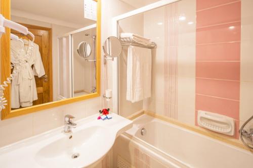 a bathroom with a sink and a tub and a mirror at Hotel Bel Azur Thalasso & Bungalows in Hammamet