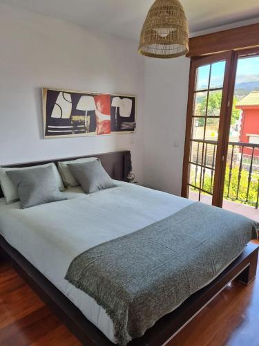 a bedroom with a large bed and a large window at Un Chalecito en Cantabria in Periedo
