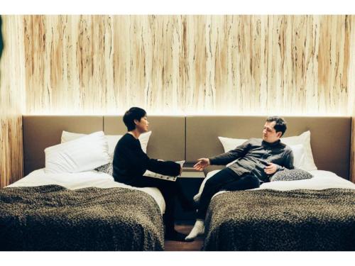 two men are sitting on beds in a room at THE BOLY OSAKA - Vacation STAY 52779v in Osaka