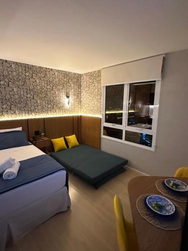 a hotel room with a bed and a table and a window at Loft de Luxo no Bairro mais nobre de Goiânia in Goiânia