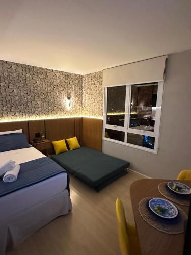 ein Hotelzimmer mit einem Bett, einem Tisch und einem Fenster in der Unterkunft Loft de Luxo no Bairro mais nobre de Goiânia in Goiânia