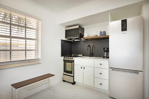 a kitchen with white cabinets and a refrigerator at La Mer Suites in Fort Lauderdale