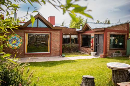 una casa de ladrillo con un patio con césped en Posada Pesca Aike Patagonico en Los Antiguos