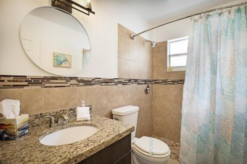 a bathroom with a sink and a toilet and a mirror at La Mer Suites in Fort Lauderdale