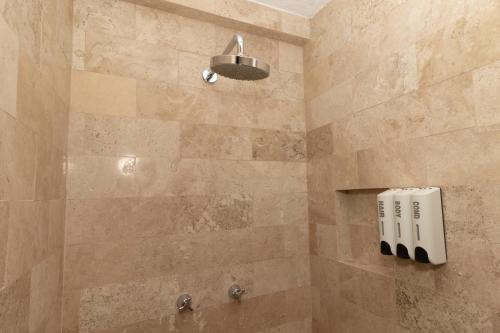 y baño con ducha y pared de piedra. en Hotel Yahalis, en Jilotepec de Abasolo