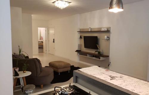 Sala de estar con sofá, silla y TV en Apartamento Residencial Bordô amplo 3 quartos próximo à praia, en Itapema