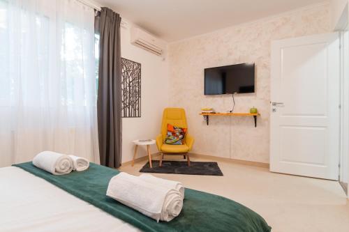 a bedroom with a bed and a yellow chair at NEW Iorga3 OldCity SelfCheckIn in Timişoara