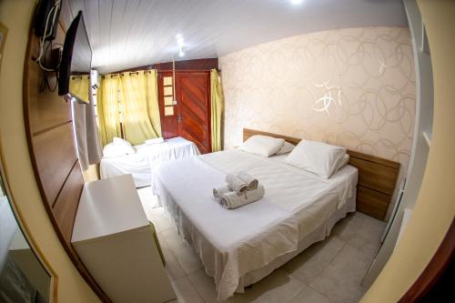 um pequeno quarto com 2 camas e lençóis brancos em Recanto dos Corais em Fernando de Noronha