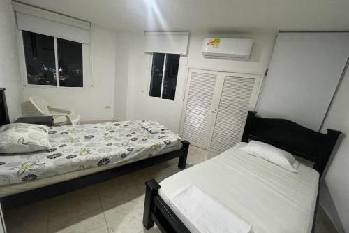 Un dormitorio con 2 camas y una silla. en Apartamento hermosa Vista al Mar en el Rodadero Santa Marta, en Santa Marta