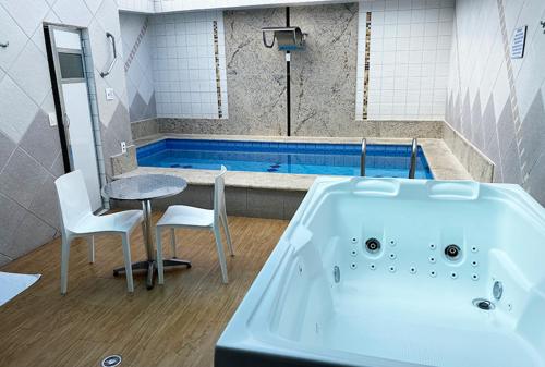 a bathroom with a bath tub and a table and chairs at MOTEL 2000 in Sao Paulo