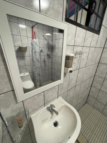 La salle de bains est pourvue d'un lavabo, d'un miroir et de toilettes. dans l'établissement oasis natural en un paraiso tropical, à El Espino