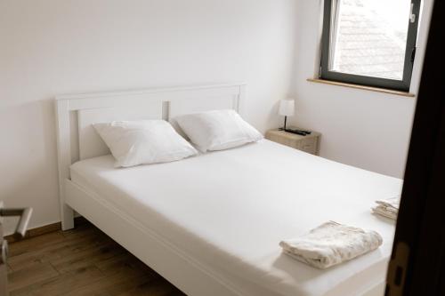 a white bed with two pillows and a window at Backspace Apartments in Vršac