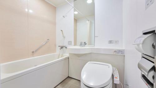 a white bathroom with a toilet and a sink at Daiwa Roynet Hotel Morioka in Morioka