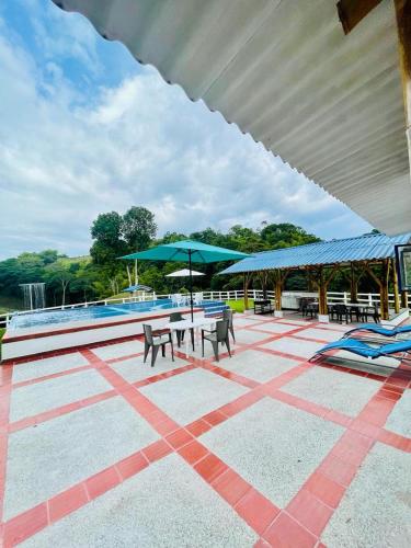 un patio con tavoli e ombrelloni accanto alla piscina di Finca Venecia de Techo Azul en la tebaida a La Tebaida