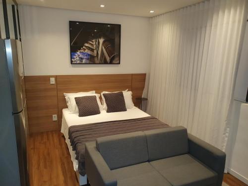 ein kleines Schlafzimmer mit einem Bett und einem Sofa in der Unterkunft Studio Aconchegante in São Paulo