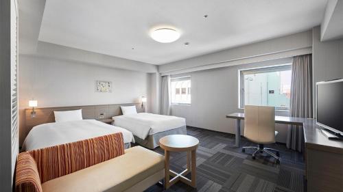 ein Hotelzimmer mit 2 Betten und einem Schreibtisch in der Unterkunft Daiwa Roynet Hotel Morioka in Morioka