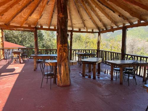 um pavilhão de madeira com mesas e cadeiras sob um telhado em Restaurant y Hostería El Tucán em San José de Maipo