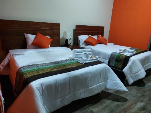 2 camas en una habitación de hotel con tazas y platos en La Finka Cajamarca en Cajamarca