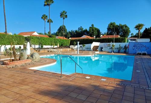 een groot zwembad in een resort met palmbomen bij Bungalow en el sur de Gran Canaria in Las Palmas de Gran Canaria