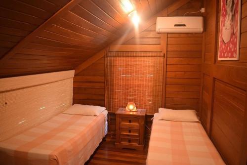 1 dormitorio en el ático con 2 camas y mesita de noche en Acomodações Ibirawave en Imbituba