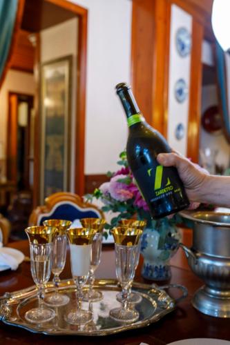 a person holding a bottle of wine on a table with glasses at Hotel Bosnali in Adana