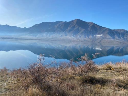 a reflection of a mountain in a body of water at Cosy 1960's Kiwi Holiday House in Omarama