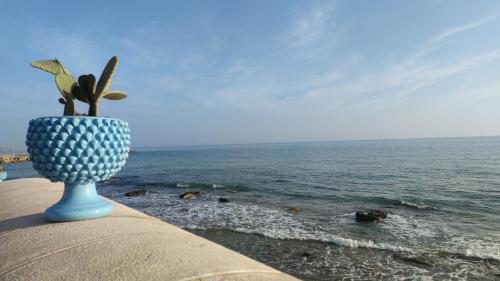 a blue vase sitting on a wall next to the ocean at L' Attico di Kely in Santa Elisabetta