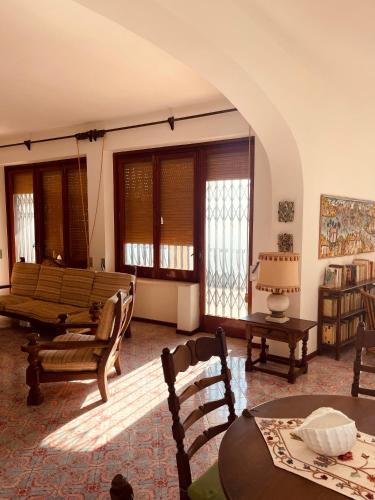 a living room with a couch and tables and windows at Villa Rosanna in Massa Lubrense