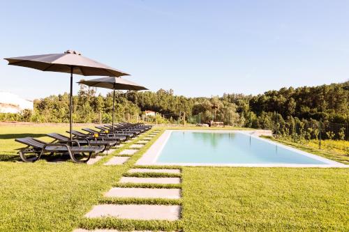 a swimming pool with lounge chairs and an umbrella at A Casa da Quintã - Piscina exterior e interior aquecida in Cabeceiras de Basto