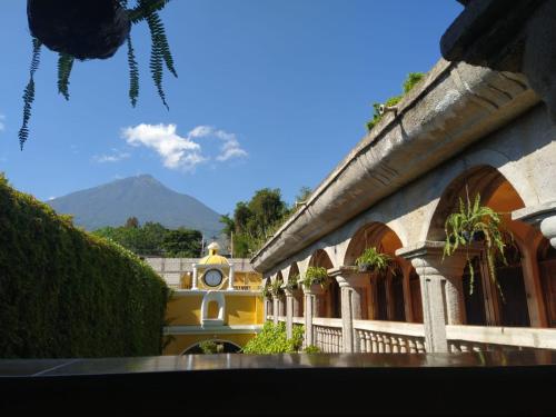 Ciudad Vieja Bed & Breakfast Hotel في غواتيمالا: مبنى عليه ساعه وفيه جبل في الخلف