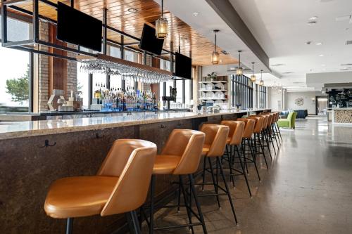 a bar with a row of brown bar stools at Hotel Indigo Traverse City, an IHG Hotel in Traverse City