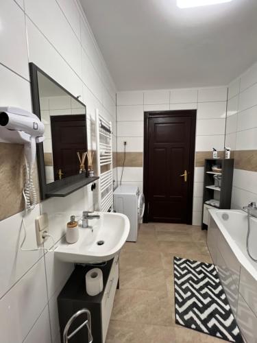 a bathroom with a sink and a tub and a mirror at Gera Apartment in Gera
