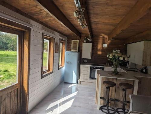 a kitchen with a refrigerator and a counter with stools at Gorgeous countryside cabin in Lyminge