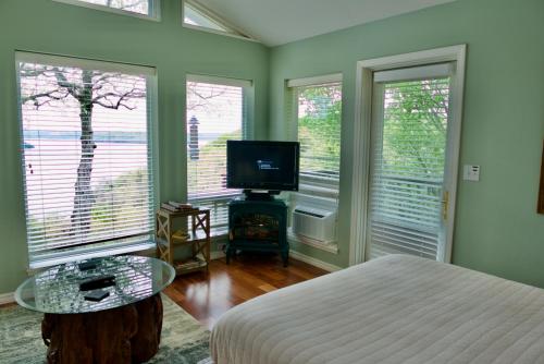 a bedroom with a bed and a tv and windows at Beaver Lake Cottages in Eureka Springs