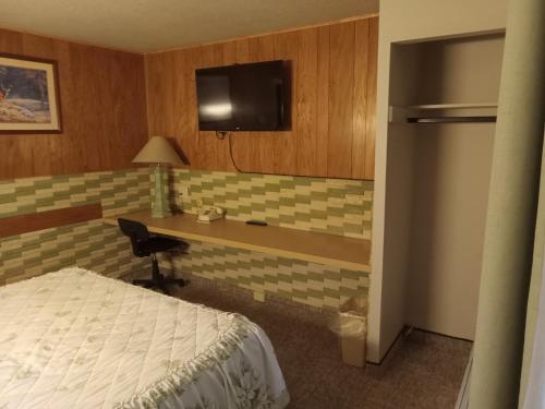 Dormitorio con escritorio, cama y TV en Siesta Motel en Havre