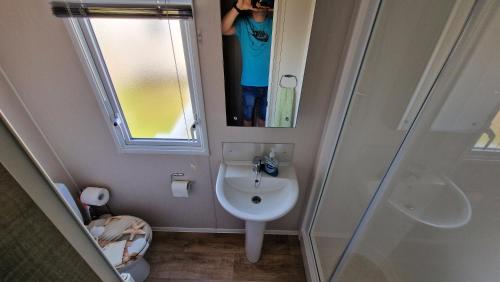 a person taking a picture of a bathroom with a sink at Seaside Heaven - Southerness Caravan Rental in Mainsriddle