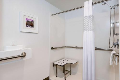 Baño blanco con cortina de ducha y taburete en Hampton Inn Charlotte Uptown, en Charlotte