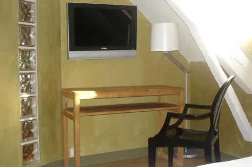 a living room with a desk and a tv and a chair at Hotel La Bastie d'Urfé in Naussac