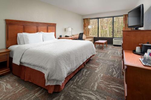 a hotel room with a bed and a flat screen tv at Hampton Inn Oak Ridge Knoxville in Oak Ridge