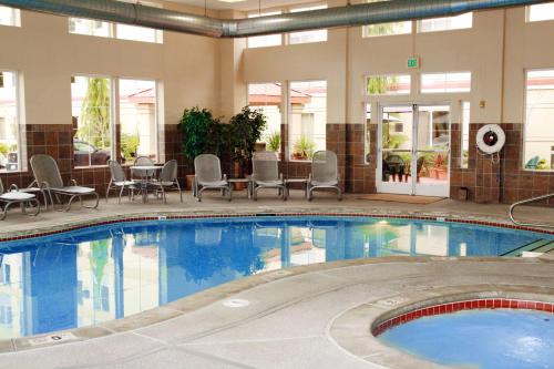 una grande piscina con sedie e tavolo in un edificio di Hampton Inn & Suites Seattle North/Lynnwood a Lynnwood