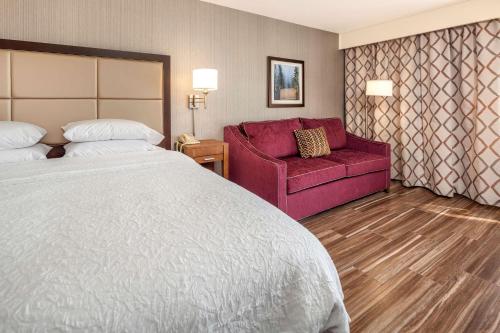 ein Hotelzimmer mit einem Bett und einem roten Sofa in der Unterkunft Hampton Inn & Suites Seattle North/Lynnwood in Lynnwood