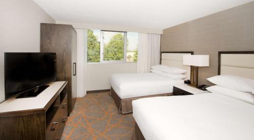 a hotel room with two beds and a flat screen tv at Embassy Suites by Hilton Cincinnati Northeast - Blue Ash in Blue Ash