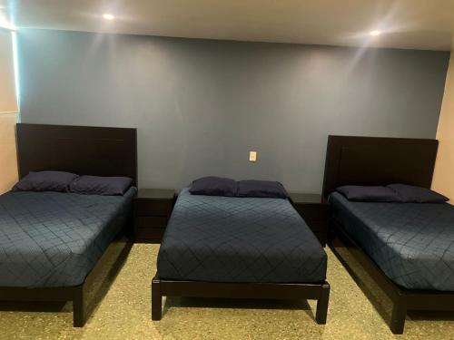 two beds in a room with blue sheets at Hotel Casa-Noria Acapulco in Acapulco