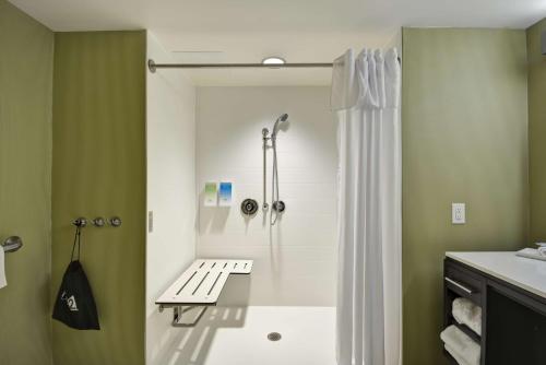 y baño con ducha y banco. en Home2 Suites By Hilton Oswego, en Oswego