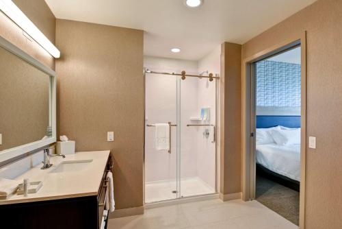 a bathroom with a shower and a sink and a bed at Home2 Suites By Hilton Palmdale in Palmdale