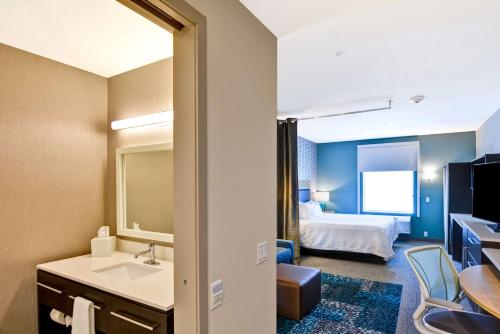 a bathroom with a sink and a bedroom with a bed at Home2 Suites By Hilton Palmdale in Palmdale