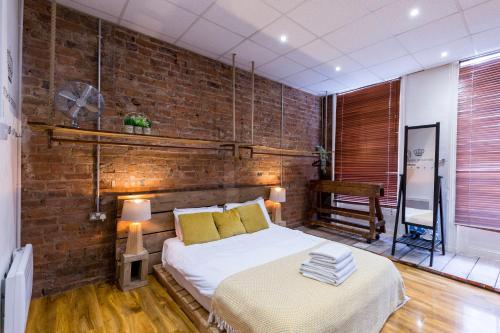 Un dormitorio con una cama y una pared de ladrillo. en City Centre Vintage Chic Studio, en Mánchester
