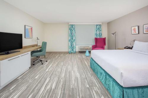 a hotel room with a bed and a desk and a tv at Hilton Garden Inn Surprise Phoenix in Surprise