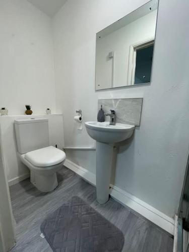 a white bathroom with a toilet and a sink at Luxury new studio flat in Luton